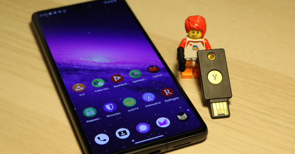 Smartphone with open source apps and a Lego figure holding a Yubikey